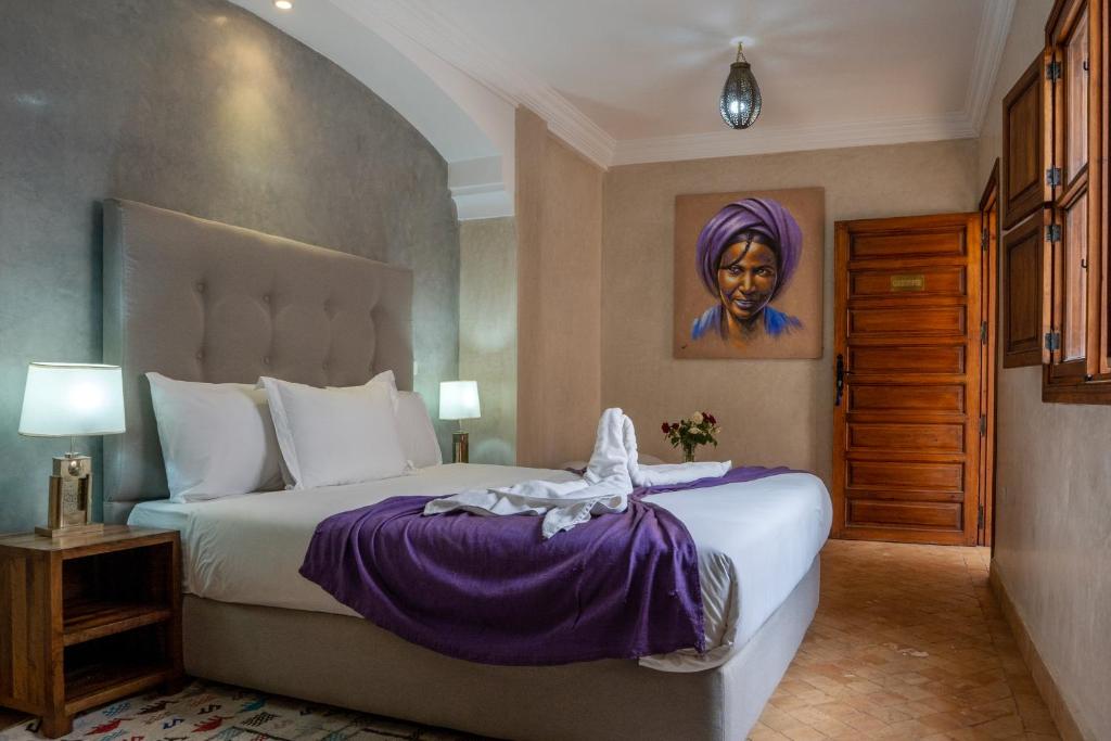 - une chambre avec un lit et une peinture d'une femme dans l'établissement Riad Le Plein Sud, à Marrakech