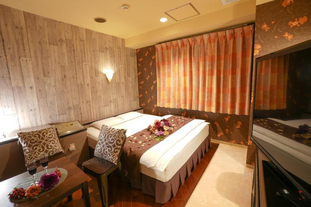 une chambre d'hôtel avec un lit, une table et un bureau dans l'établissement Hotel Jupiter (Adult Only), à Hiroshima