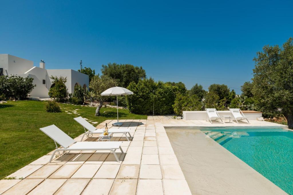une piscine avec des chaises et un parasol à côté d'une maison dans l'établissement New Villa Filara with Sea view Pool, à Specchiolla