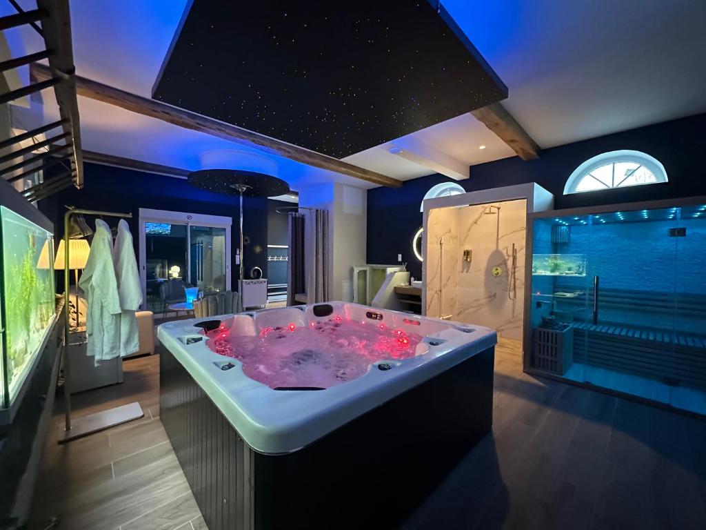 une grande salle de bain avec une grande baignoire à l'eau rose dans l'établissement Au Domaine du Prédieu, à Crécy-sur-Serre