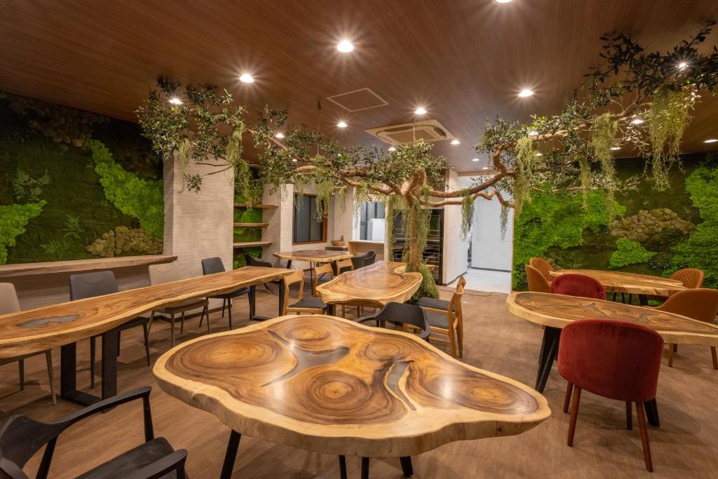un restaurant avec des tables et des chaises en bois et un mur vert dans l'établissement Yumura Onsen MIDORIYA, à Yumura