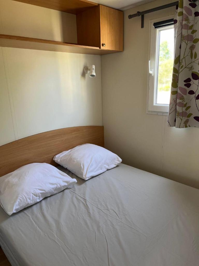 - 2 oreillers sur un lit dans une chambre avec fenêtre dans l'établissement Bungalow à l'asinerie, à Jau-Dignac-et-Loirac 4 autres photos