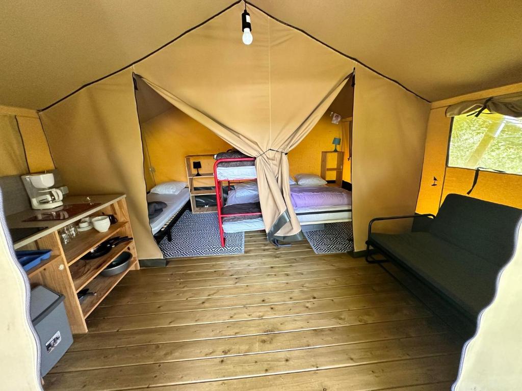 Cette chambre comprend une tente avec un lit et un canapé. dans l'établissement LES EYCHECADOUS, à Artigat