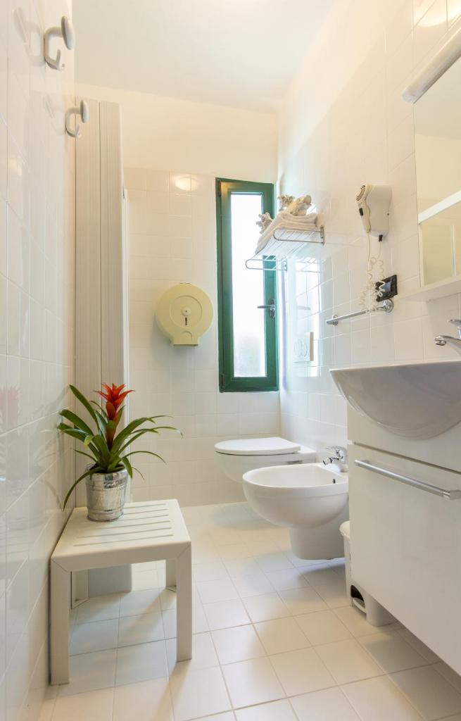 une salle de bain blanche avec toilettes et lavabo dans l'établissement Hotel Olanda, à Lido di Jesolo