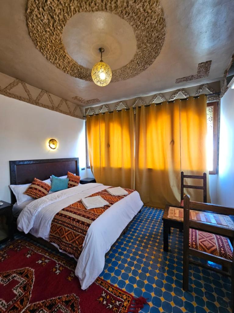 - une chambre avec un lit dans une pièce dotée de rideaux jaunes dans l'établissement Riad Merzouga Dunes, à Merzouga