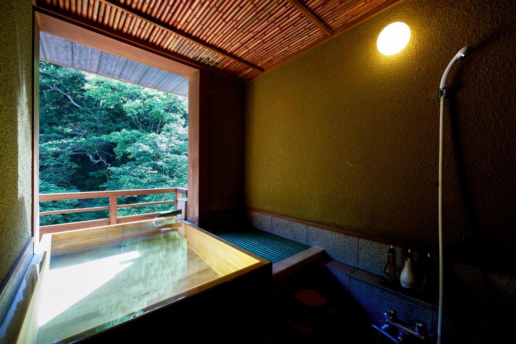 La salle de bains est pourvue d'une fenêtre et d'une baignoire avec douche. dans l'établissement Shima-Onsen Toshimaya, à Nakanojo