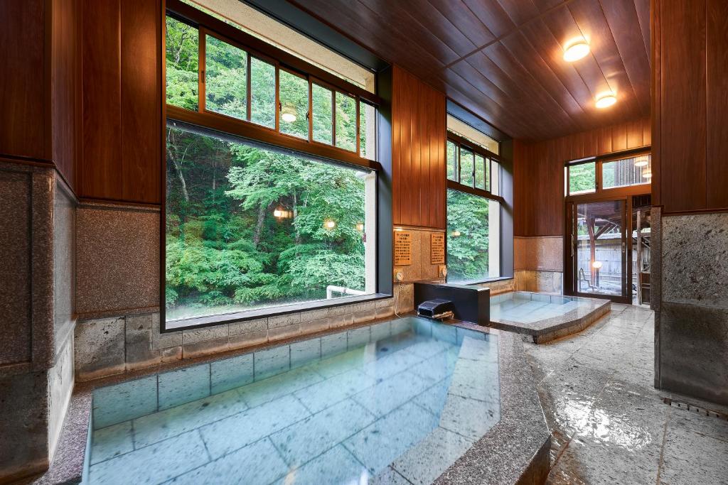 - une piscine intérieure dans une maison dotée d'une grande fenêtre dans l'établissement Shima-Onsen Toshimaya, à Nakanojo