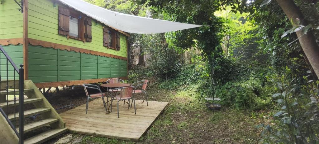 un patio avec une table et des chaises sur une terrasse dans l'établissement roulotte Tipergwendiou, à Plougonvelin