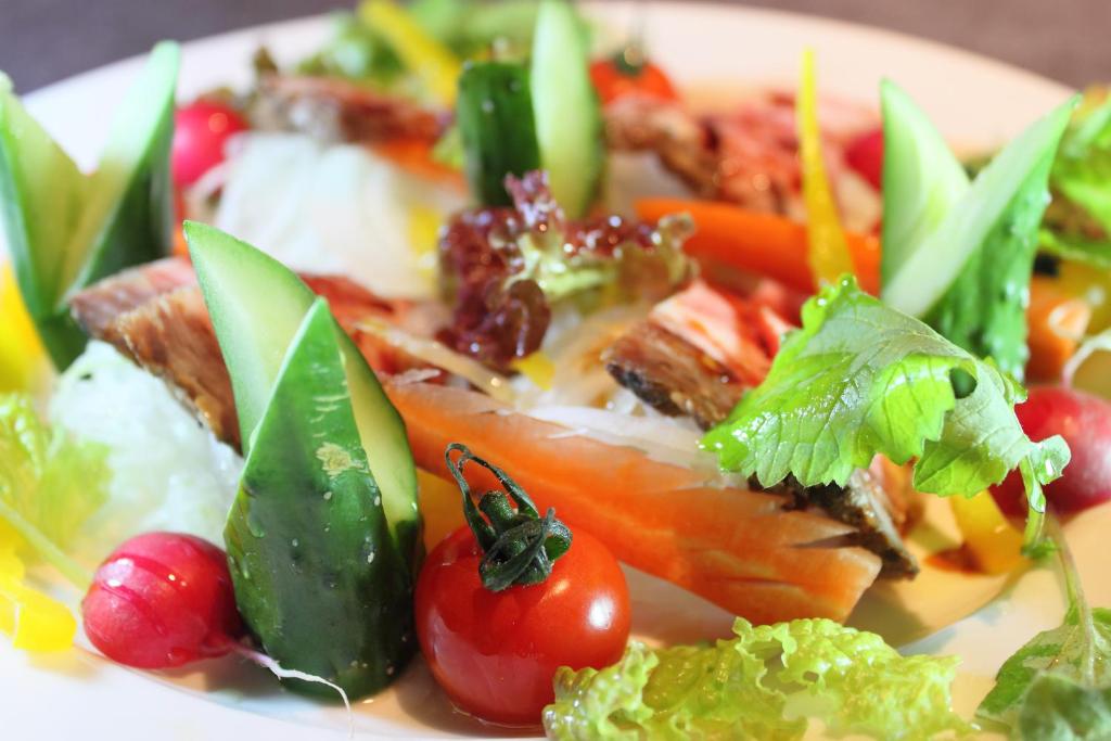 une plaque de nourriture contenant des tomates et des légumes dans l'établissement ホテル南の風風力3駒ヶ根店, à Komagane