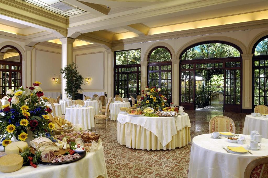 une salle de banquet avec des tables blanches et des fleurs. dans l'établissement Grand Hotel Royal, à Viareggio 71 autres photos