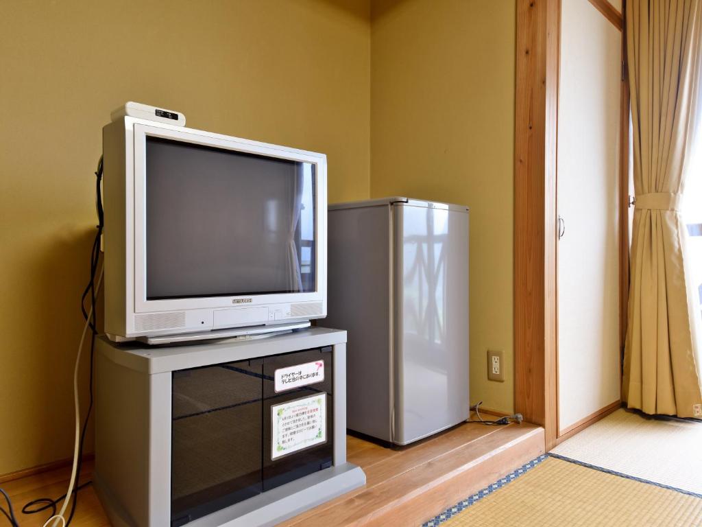 une télévision posée sur une commode avec un réfrigérateur dans l'établissement 守実温泉　やすらぎの郷やまくに, à Morizane