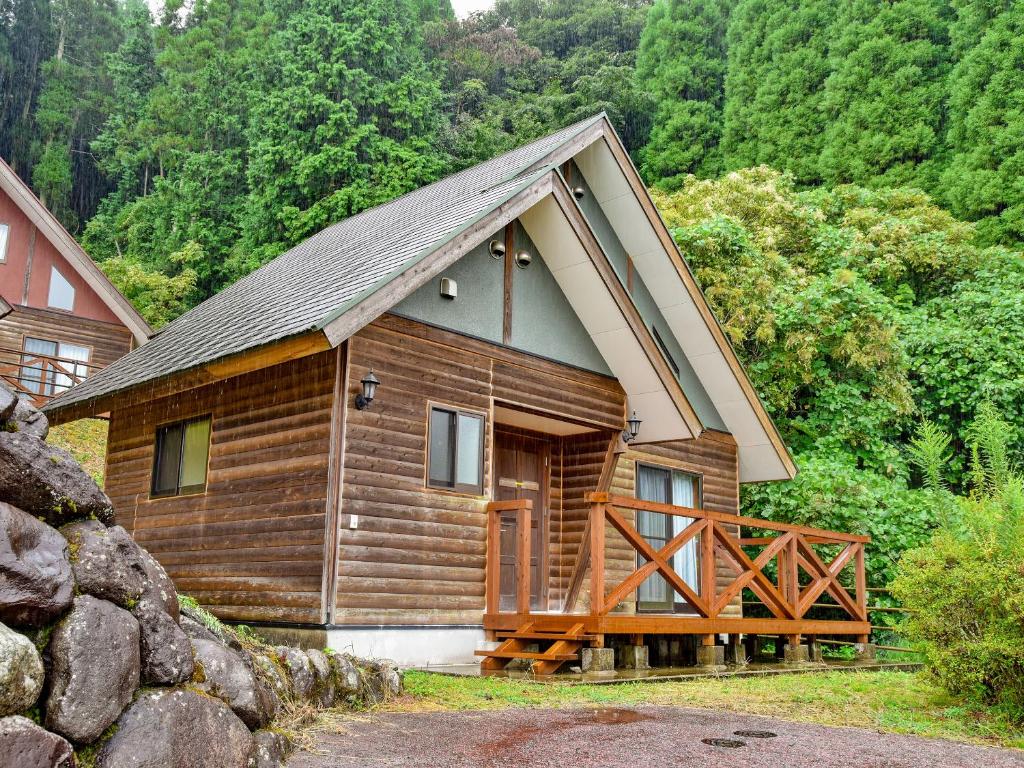 une cabane en bois avec un grand porche dans les bois dans l'établissement 守実温泉　やすらぎの郷やまくに, à Morizane