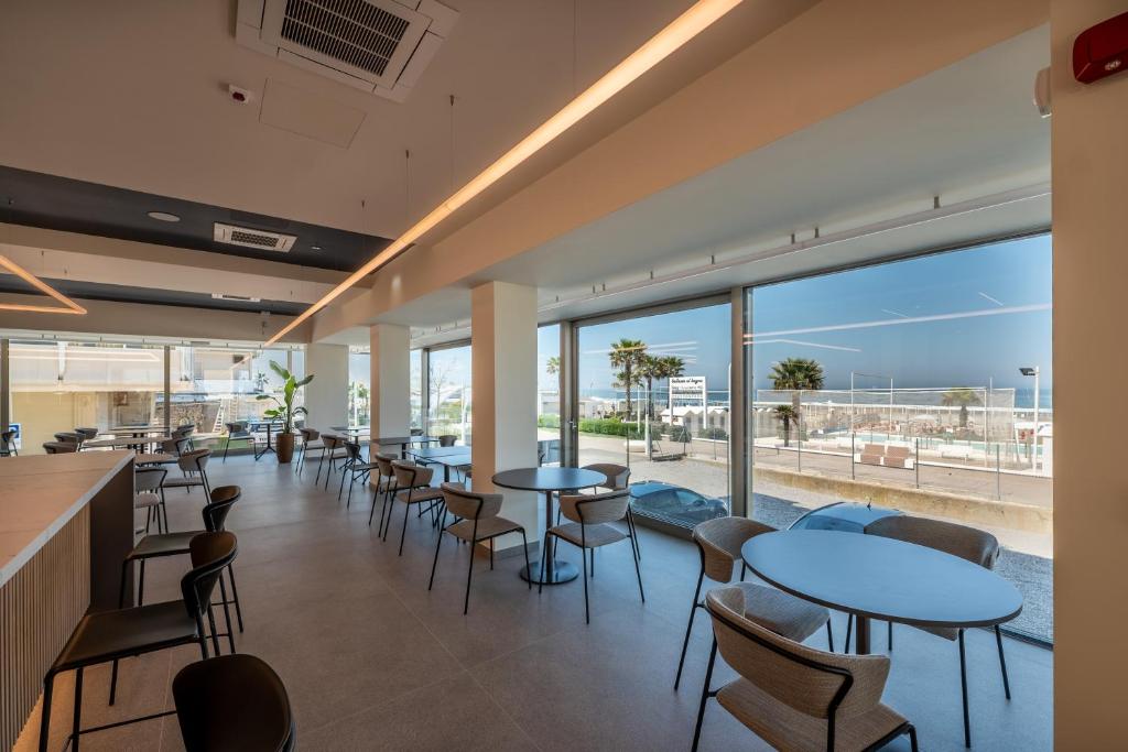 un restaurant avec des tables et des chaises et une vue sur l'océan dans l'établissement Hotel Sporting Riccione, à Riccione