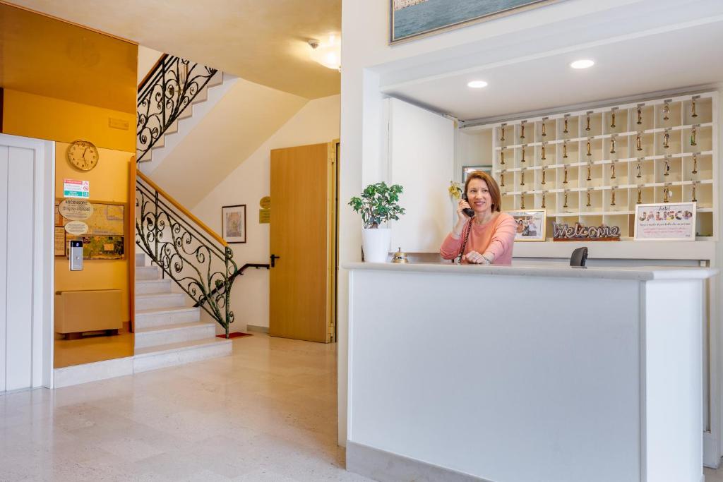 une femme se tenant derrière un comptoir et parlant sur un téléphone portable dans l'établissement Hotel Jalisco, à Lido di Jesolo 71 autres photos