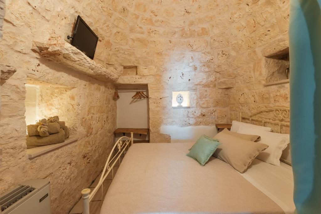 une chambre avec un lit dans un mur de pierre dans l'établissement Trulli Olea with Pool, à San Vito dei Normanni
