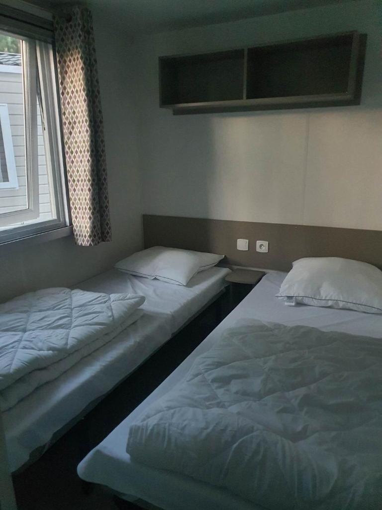 deux lits jumeaux dans une chambre avec fenêtre dans l'établissement Camping 4 étoiles Le bois dormant, à Saint-Jean-de-Monts 13 autres photos