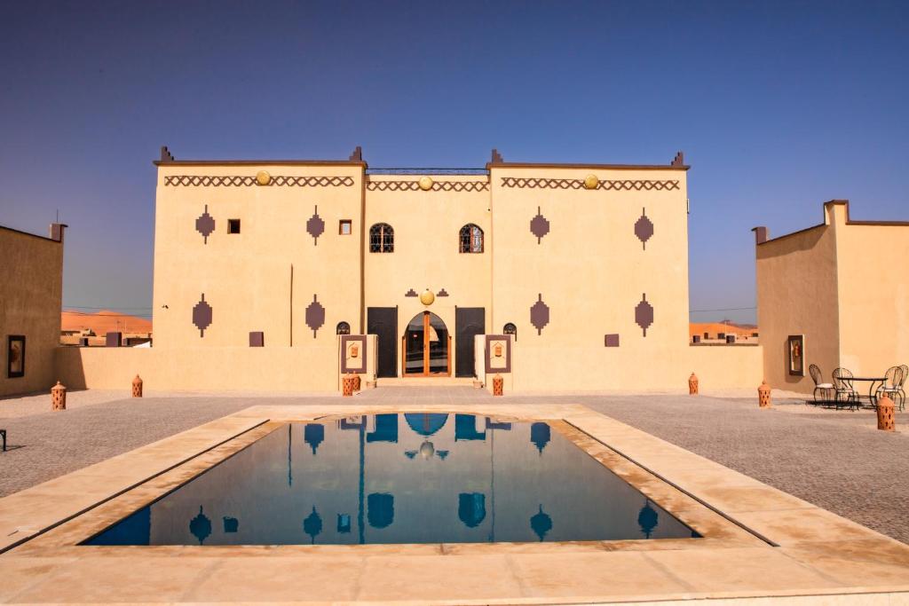 un bâtiment avec une piscine devant dans l'établissement Riad Merzouga Dunes, à Merzouga