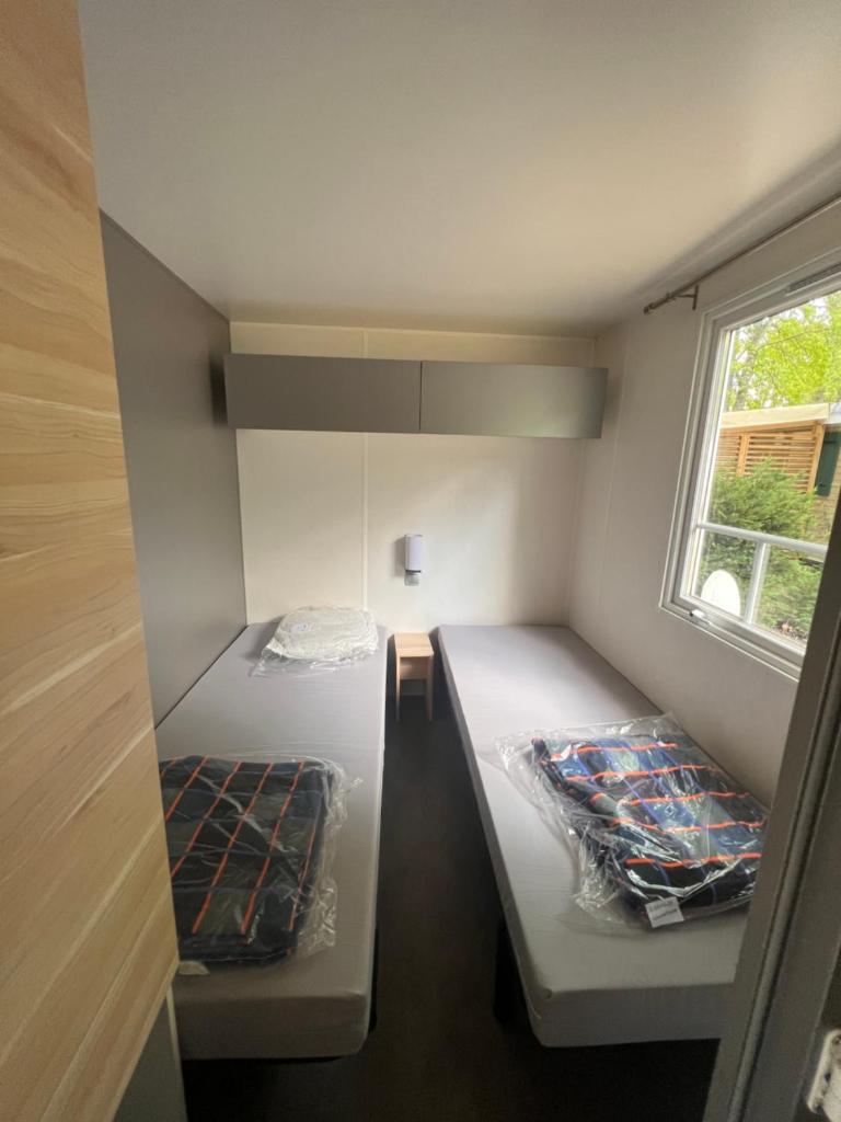une petite chambre avec deux lits et une fenêtre dans l'établissement Mobil Home du Lac - Camping 4 Étoiles, à Aureilhan 27 autres photos