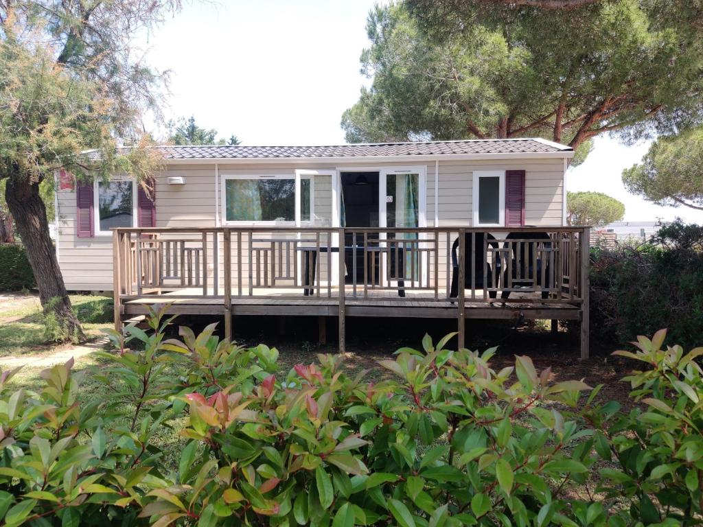 une petite maison avec un porche et une terrasse dans l'établissement Mobil Home 6/8 personnes Camping le lac des rêves, à Lattes