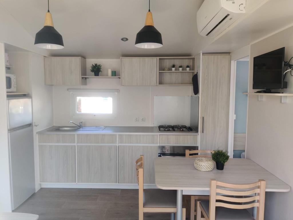 - une cuisine avec une table, des chaises et un comptoir dans l'établissement Mobil Home 6/8 personnes Camping le lac des rêves, à Lattes