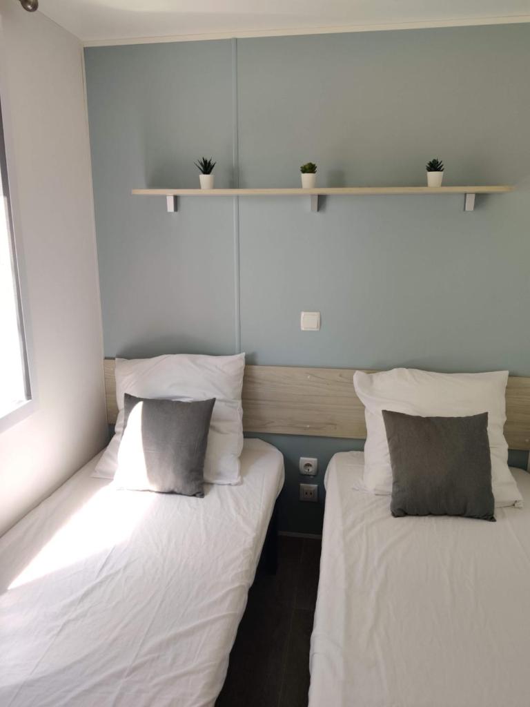 deux lits côte à côte dans une pièce dans l'établissement Mobil Home 6/8 personnes Camping le lac des rêves, à Lattes