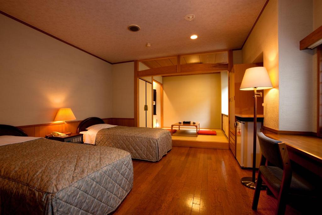 une chambre d'hôtel avec deux lits et un bureau dans l'établissement Ukiha, à Hita
