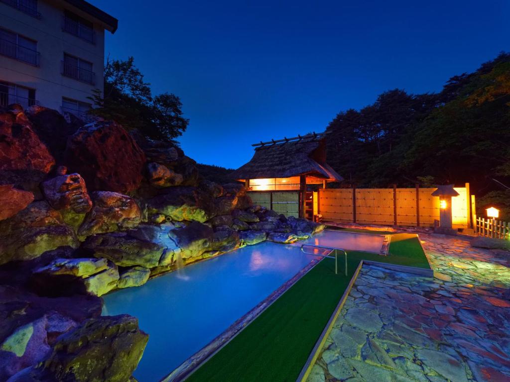 une piscine avec un mur de roche à côté d'un bâtiment dans l'établissement Ryokan Tamagoyu, à Machi-niwasaka 37 autres photos
