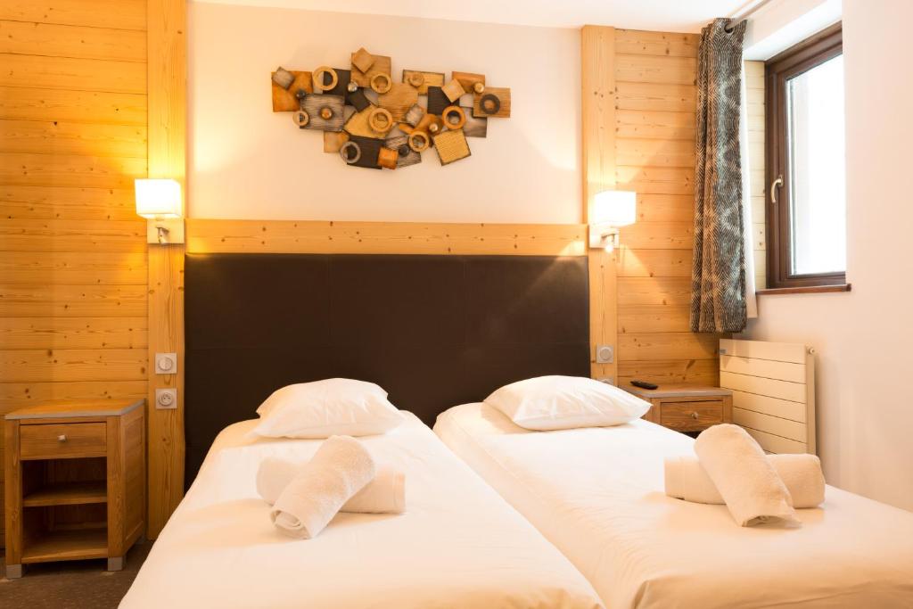 - 2 lits jumeaux dans une chambre avec une horloge sur le mur dans l'établissement Résidence Koh-I Nor by Les Etincelles, à Val Thorens