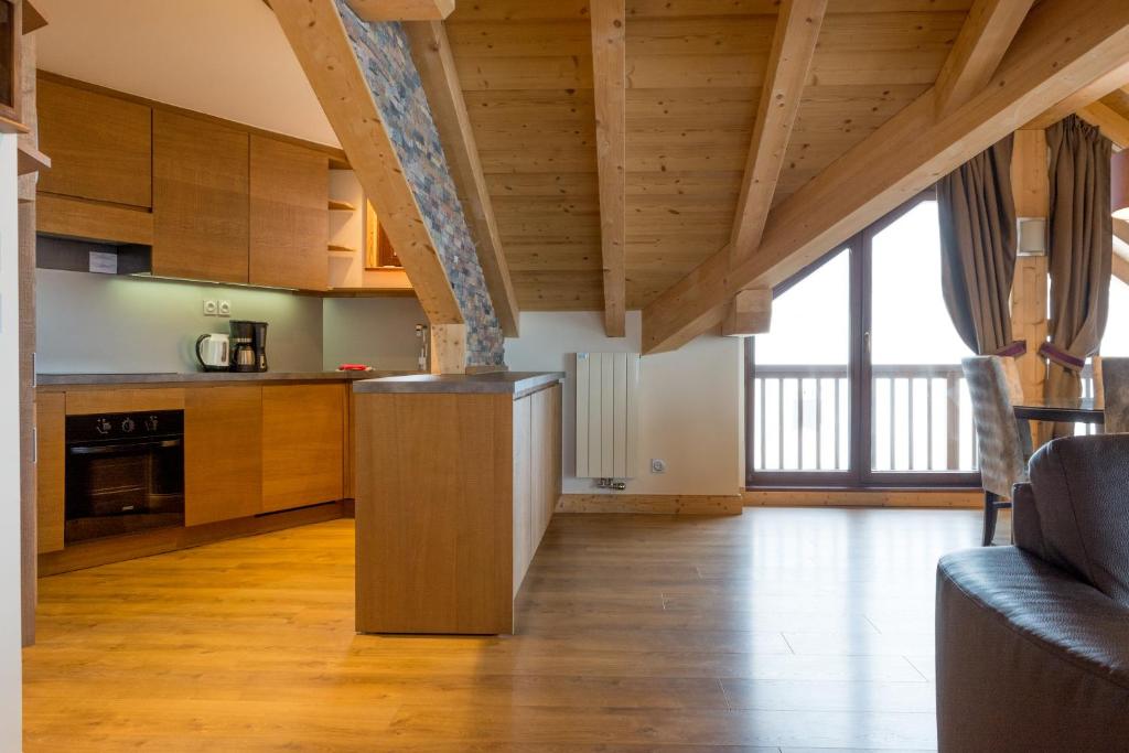 une cuisine avec des placards en bois et une grande fenêtre dans l'établissement Résidence Koh-I Nor by Les Etincelles, à Val Thorens