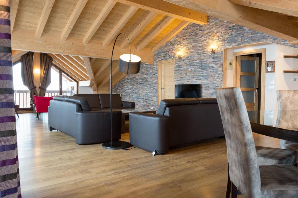 Elle comprend un salon doté d'un mobilier en cuir et d'un mur en pierre. dans l'établissement Résidence Koh-I Nor by Les Etincelles, à Val Thorens