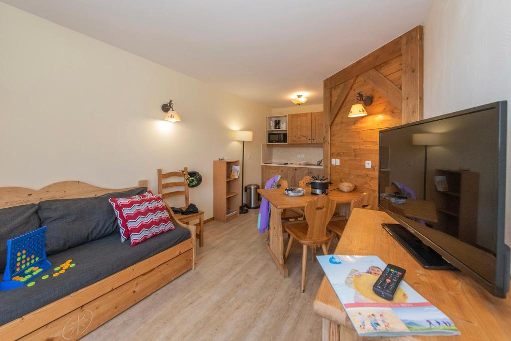 un salon avec un canapé, une télévision et une table dans l'établissement Résidence Goélia Les Alpages du Corbier, à Villarembert