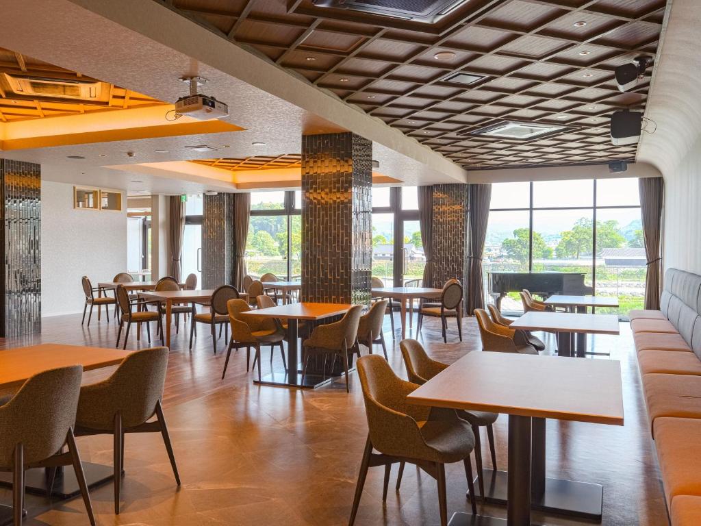 une salle à manger avec tables, chaises et fenêtres dans l'établissement Hitoyoshi Onsen Nabeya, à Hitoyoshi
