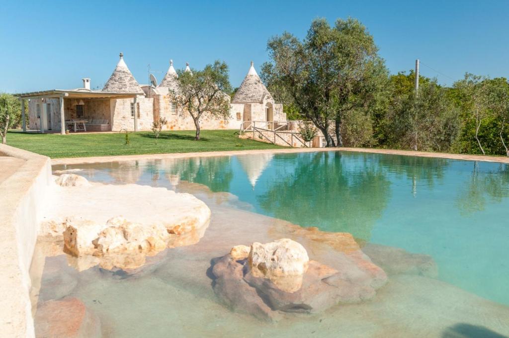 - une piscine avec un rocher dans l'eau dans l'établissement HelloApulia - Trulli tra Pietre Full, à Ceglie Messapica
