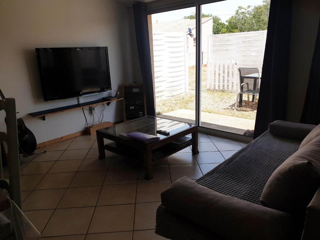 un salon avec une télévision et un canapé dans l'établissement Canal du Midi Argeliers Gîte 4 personnes, à Argeliers