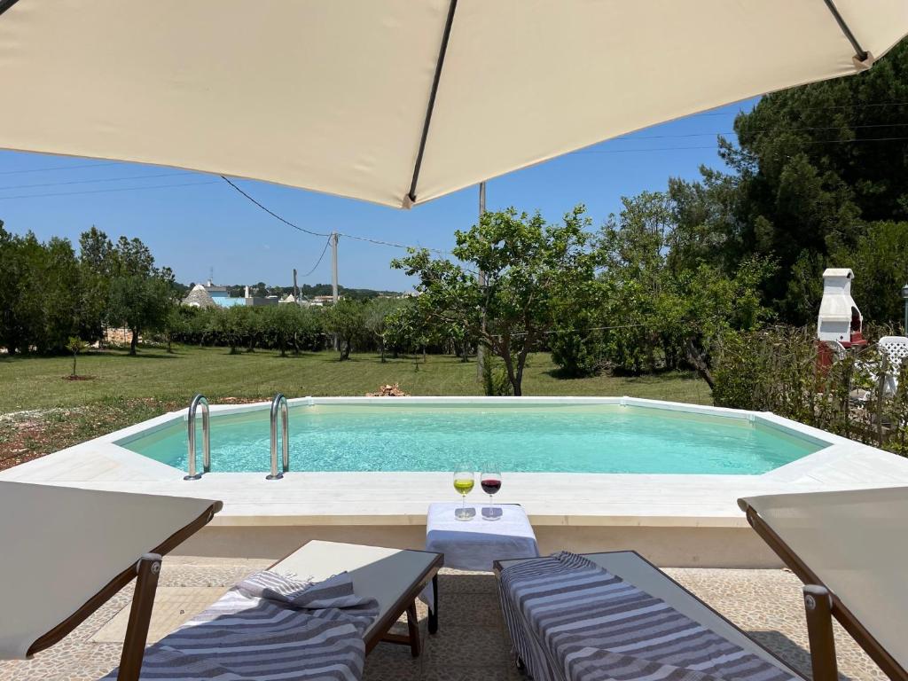 une piscine avec deux chaises et un parasol dans l'établissement Trullo Trullallero, à Martina Franca