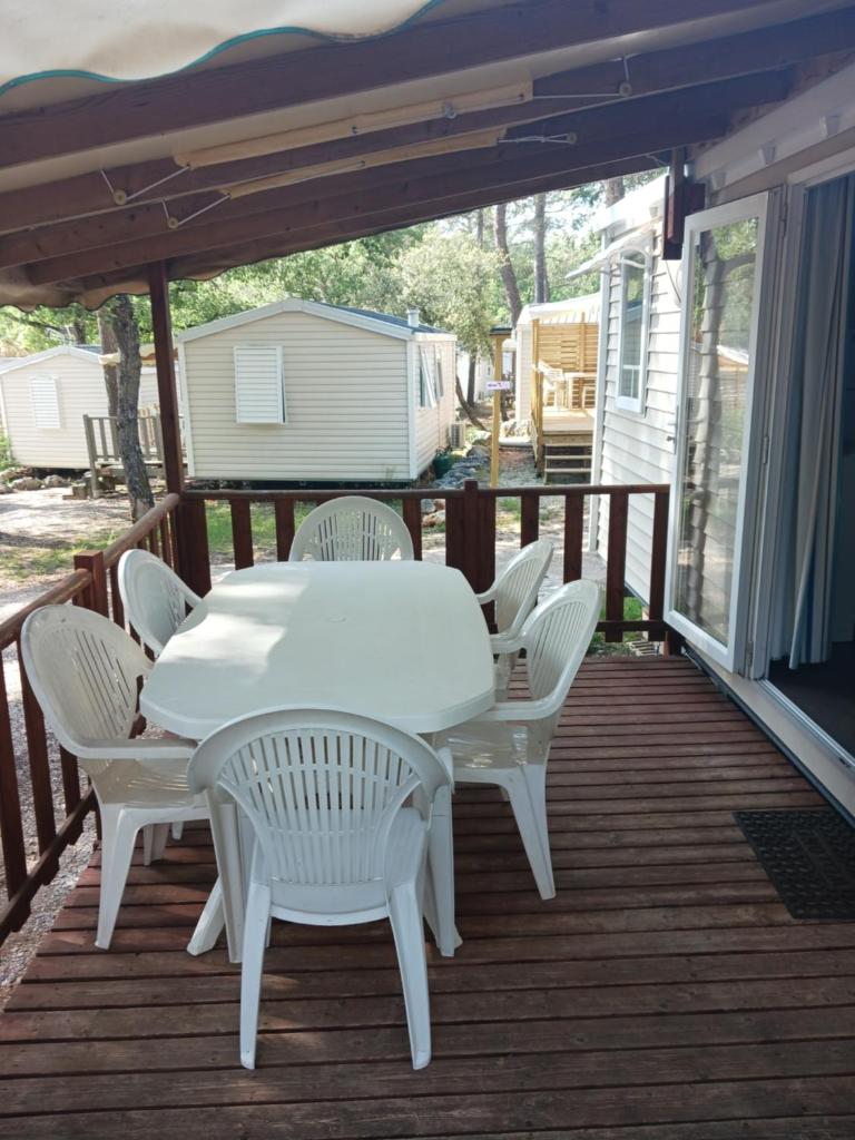 une table et des chaises blanches sur une terrasse dans l'établissement domaine de la sainte baume, à Nans-les-Pins