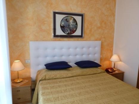 une chambre avec un lit avec deux oreillers bleus dans l'établissement Hotel Acapulco, à Lignano Sabbiadoro