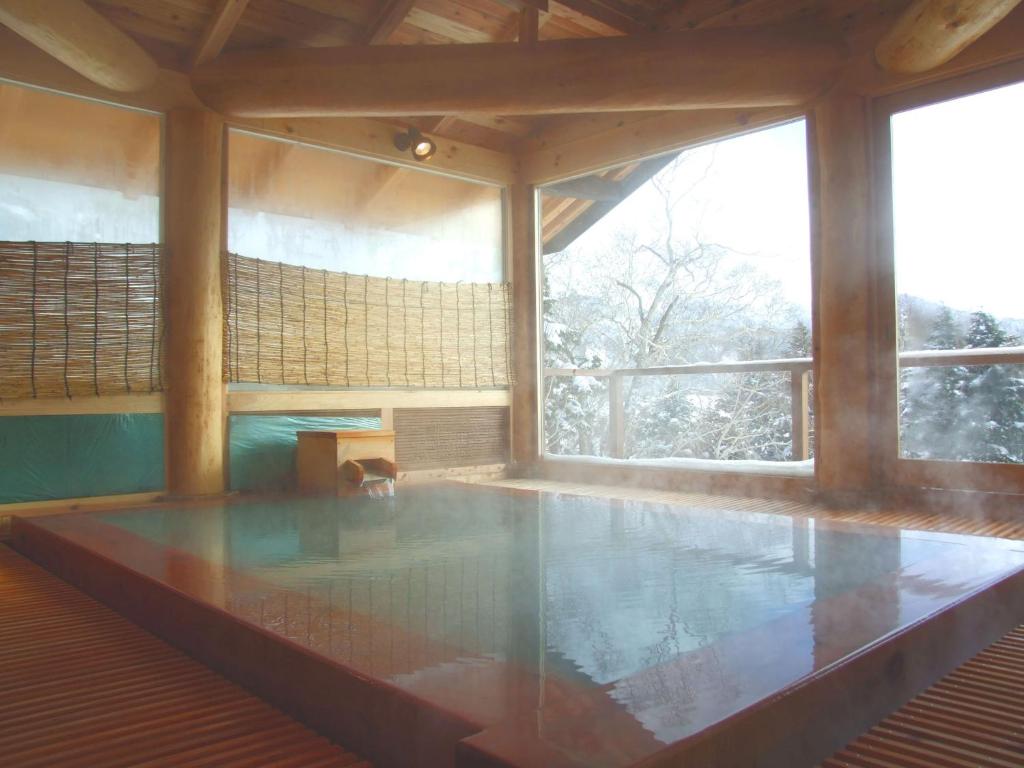 - une piscine dans une chambre dotée d'une grande fenêtre dans l'établissement Manza Onsen Nisshinkan, à Tsumagoi