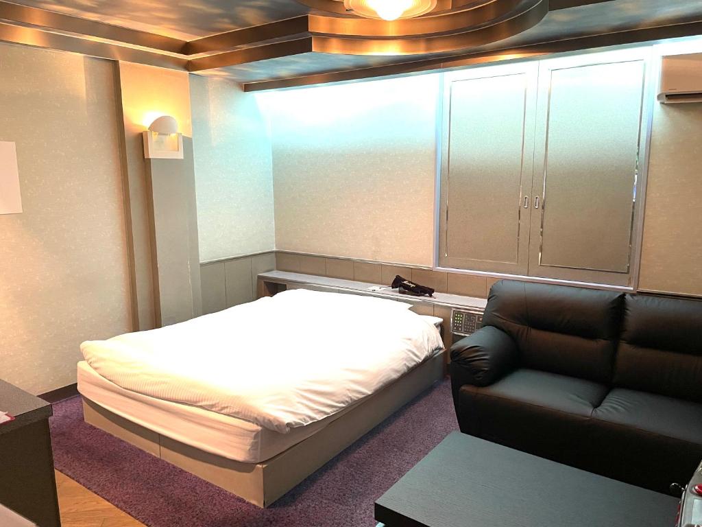 une petite chambre avec un lit et un canapé dans l'établissement Hotel Ai - coupls hotel, à Azumino