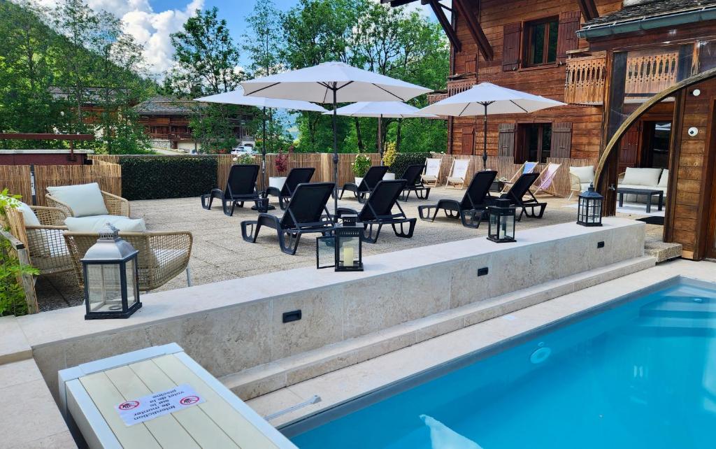 une piscine avec chaises longues et parasols dans l'établissement Hôtel et Spa Le Vermont, au Grand-Bornand