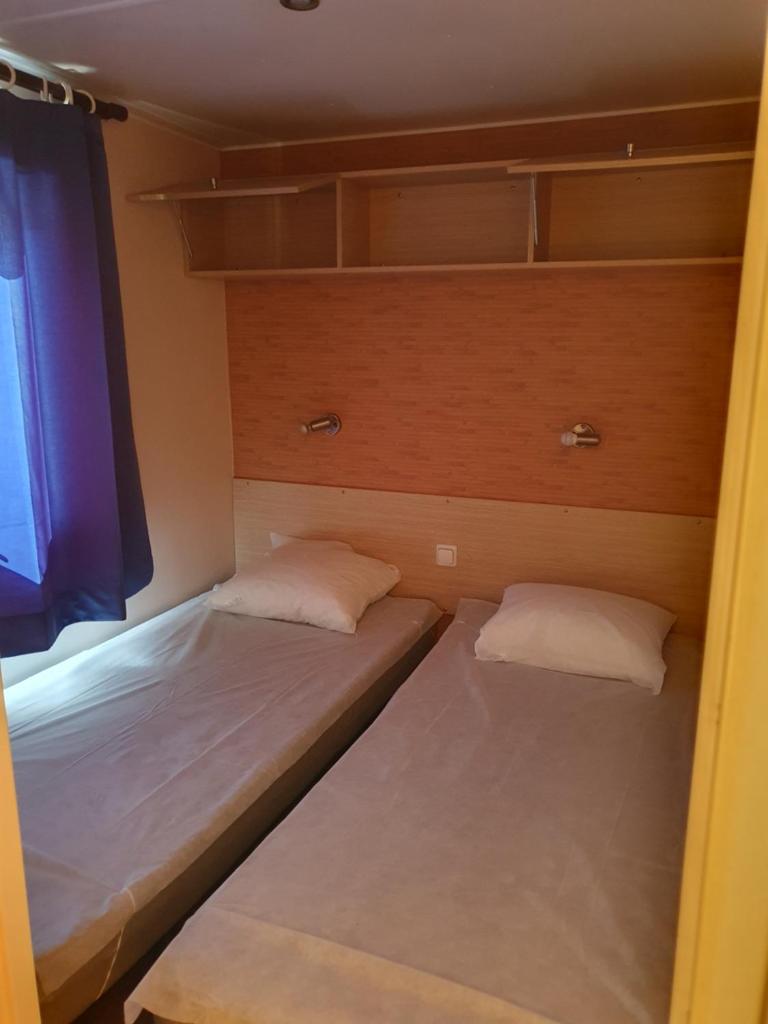 deux lits dans une petite pièce avec une fenêtre dans l'établissement Mobil-home ( dépaysement total à 40 km de paris ), à Saint-Chéron 8 autres photos