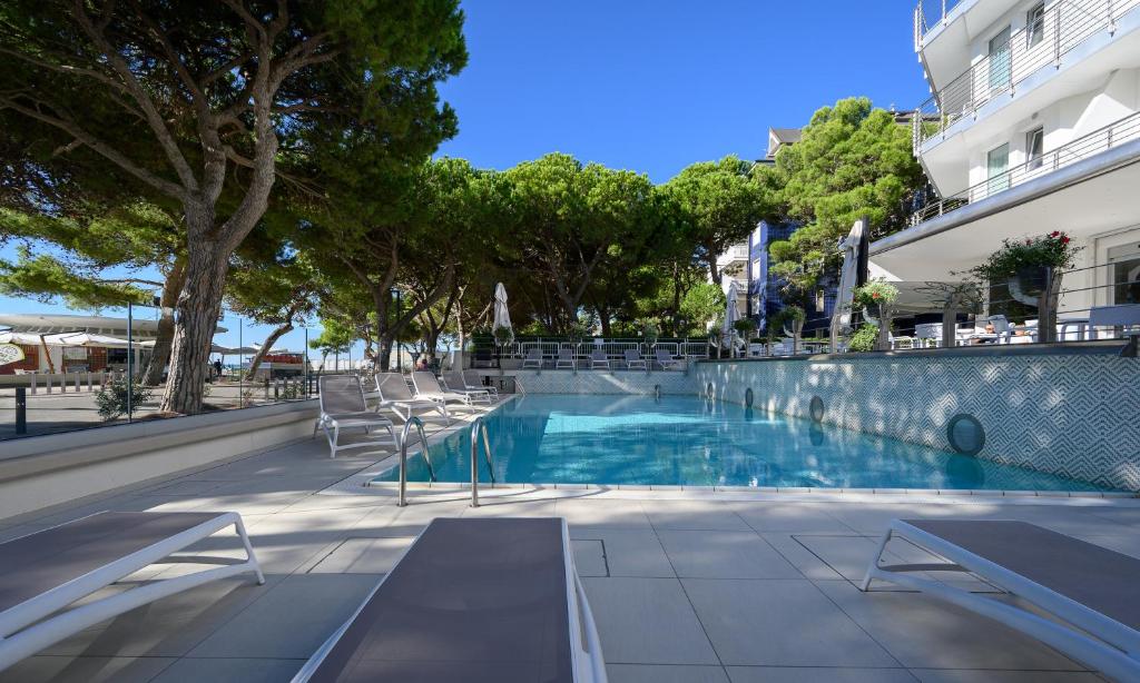 une piscine avec des chaises à côté d'un bâtiment dans l'établissement Grand Hotel Playa, à Lignano Sabbiadoro
