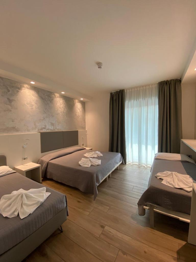 une chambre d'hôtel avec deux lits et une grande fenêtre dans l'établissement Hotel ALDEBARAN, à Lido di Jesolo