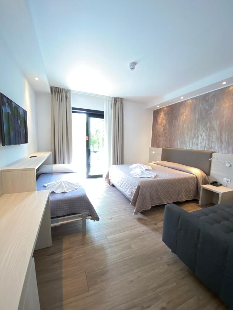 une chambre d'hôtel avec deux lits et un canapé dans l'établissement Hotel ALDEBARAN, à Lido di Jesolo