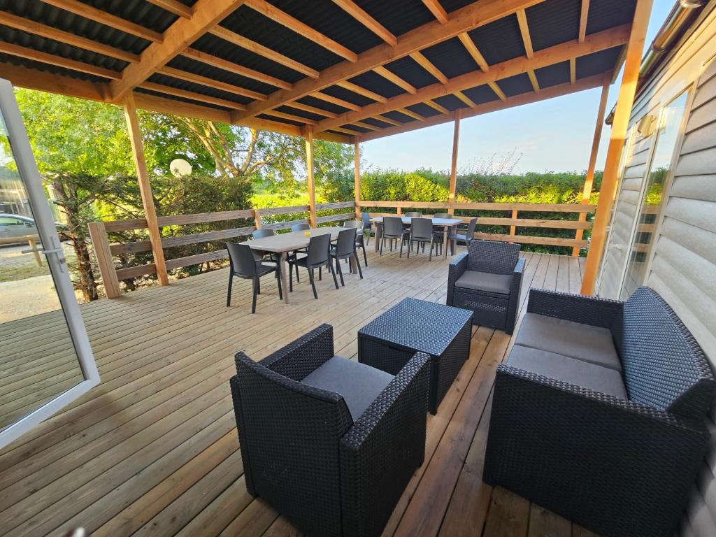 une terrasse en bois avec des tables et des chaises dessus dans l'établissement Camping Le Dolium, à Laudun-l'Ardoise