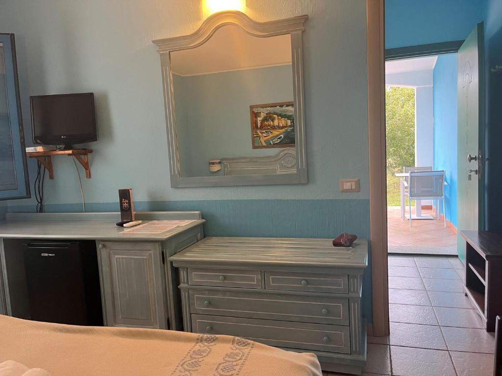 - une chambre avec un miroir, une commode et un lit dans l'établissement Hotel Baia Cea, à Bari Sardo