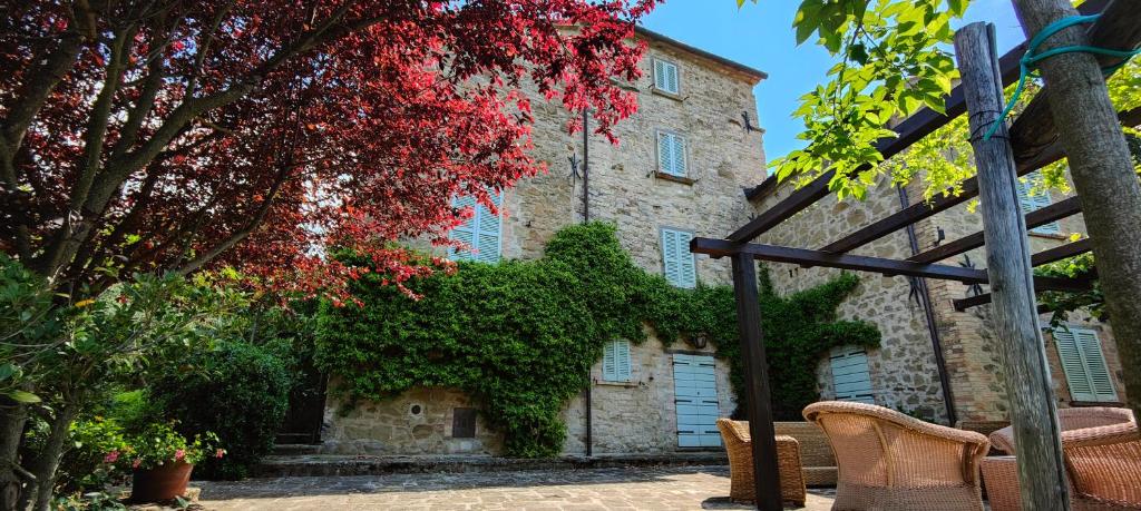 un vieux bâtiment en pierre avec des feuilles rouges et un arbre dans l'établissement Infinity pool villa - Fonte Piccola, à Città di Castello