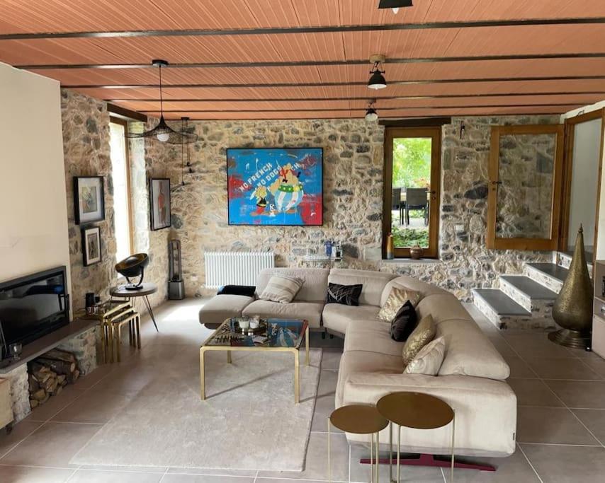 un salon avec un canapé et un mur en pierre dans l'établissement Casale del Pozzo-Villa with pool - Fosdinovo in the borgo of Pulica, à Tendola