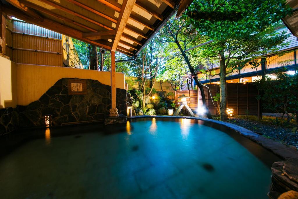 une piscine dans un jardin la nuit dans l'établissement Houshoutei, à Kaga