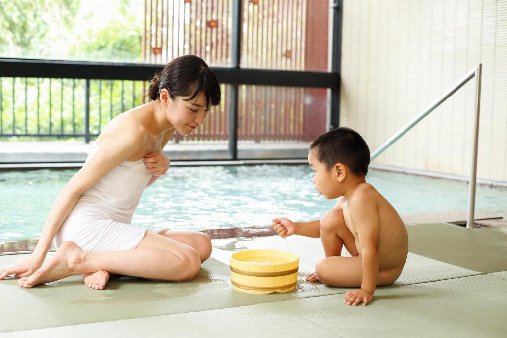 une femme et un enfant assis à côté d'une piscine dans l'établissement Houshoutei, à Kaga